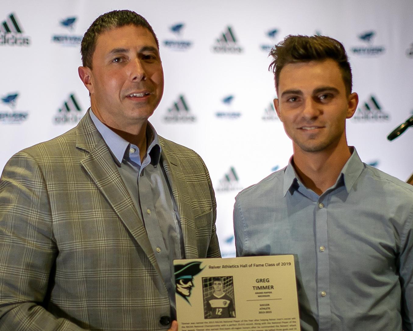 Iowa Western Director of Athletics, Jeremy Capo (left), presents Reiver Men's Soccer Alum Greg Timmer with his 2019 Hall of Fame plaque.